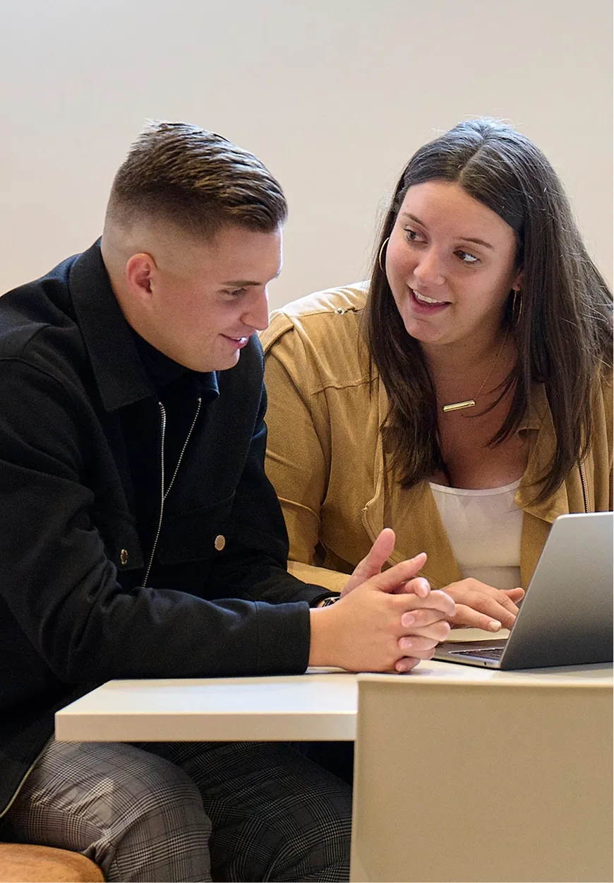 Two colleagues reviewing work together on a laptop